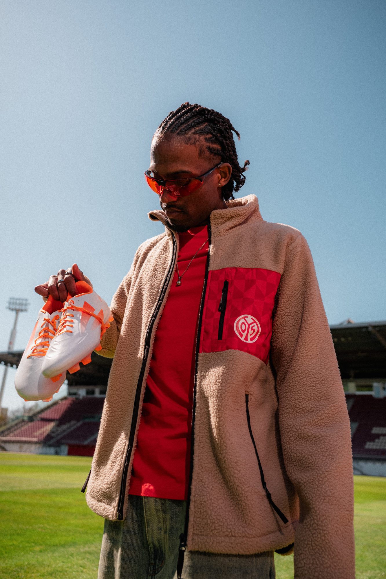 COLORBLND Model in FSV Mainz 05 Merch-Fleecejacke mit Fußballschuhen im Stadion
