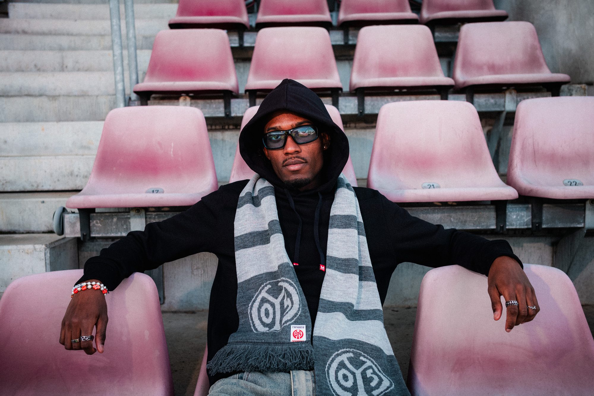 COLORBLND Model mit FSV Mainz 05 Schal in schwarzem Hoodie auf Stadionrängen