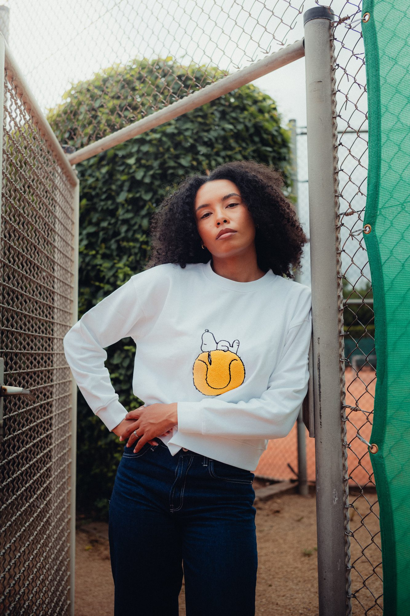 COLORBLND Model im weißen Snoopy-Sweatshirt am Tennisnetz